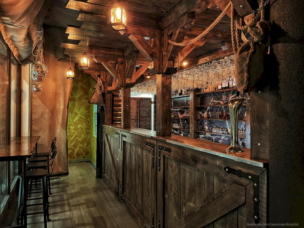 Solidny, drewniany bar jest sercem Tawerny Wilczy Dół w Krakowie.